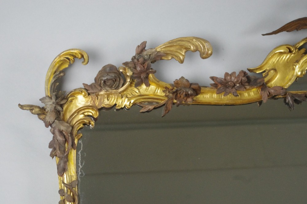 Large Victorian Rococo style giltwood overmantel mirror featuring elaborate carved foliate trails, asymmetric C-scrolls, and a scrolling top crest. View VIII