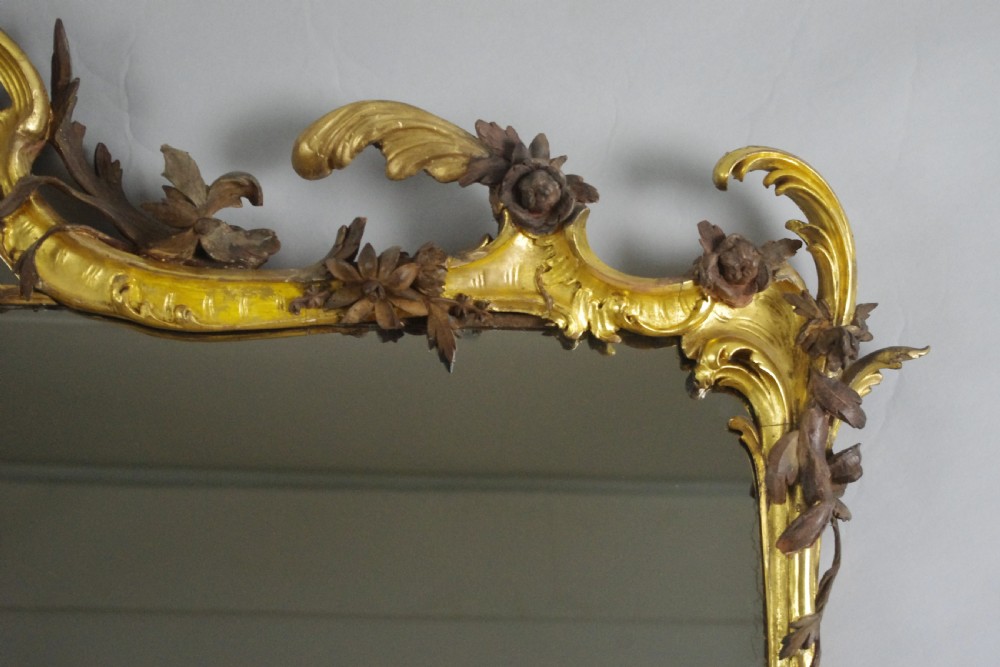 Large Victorian Rococo style giltwood overmantel mirror featuring elaborate carved foliate trails, asymmetric C-scrolls, and a scrolling top crest. View IX