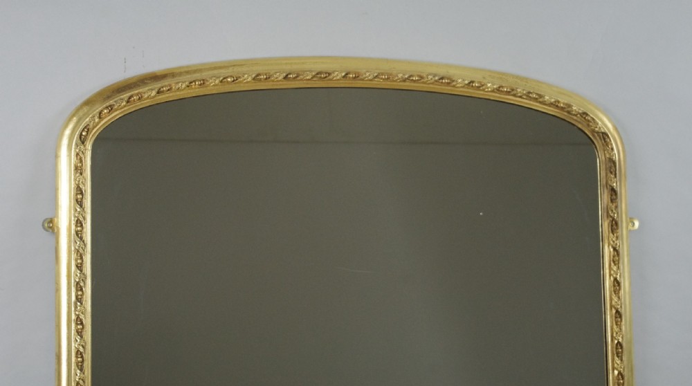 A large Victorian arched overmantel mirror featuring a gilded wooden frame decorated with detailed beadwork around the inner rim. View II