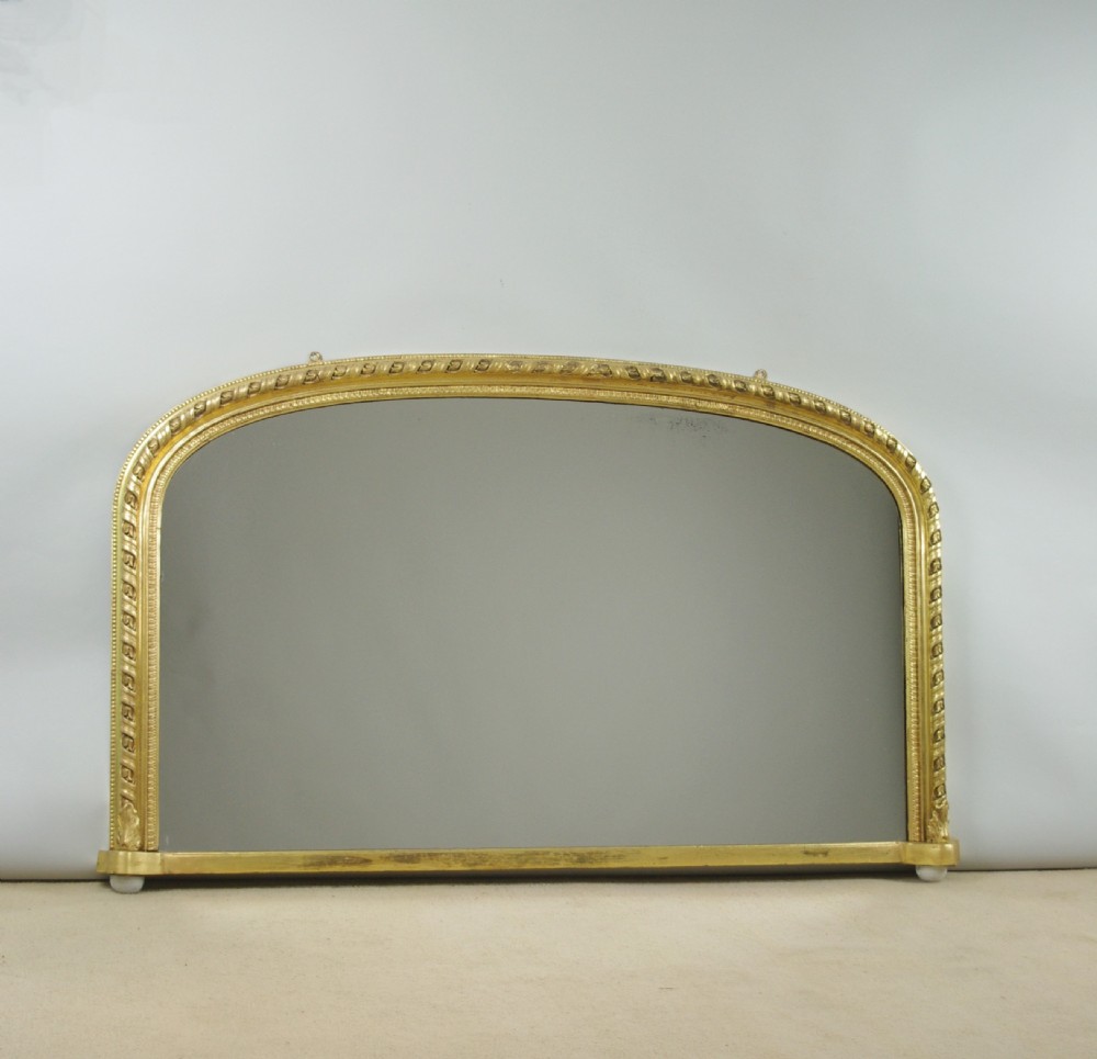 A Victorian arched overmantel mirror featuring a gilded frame with rope-twist detail and a flat base.