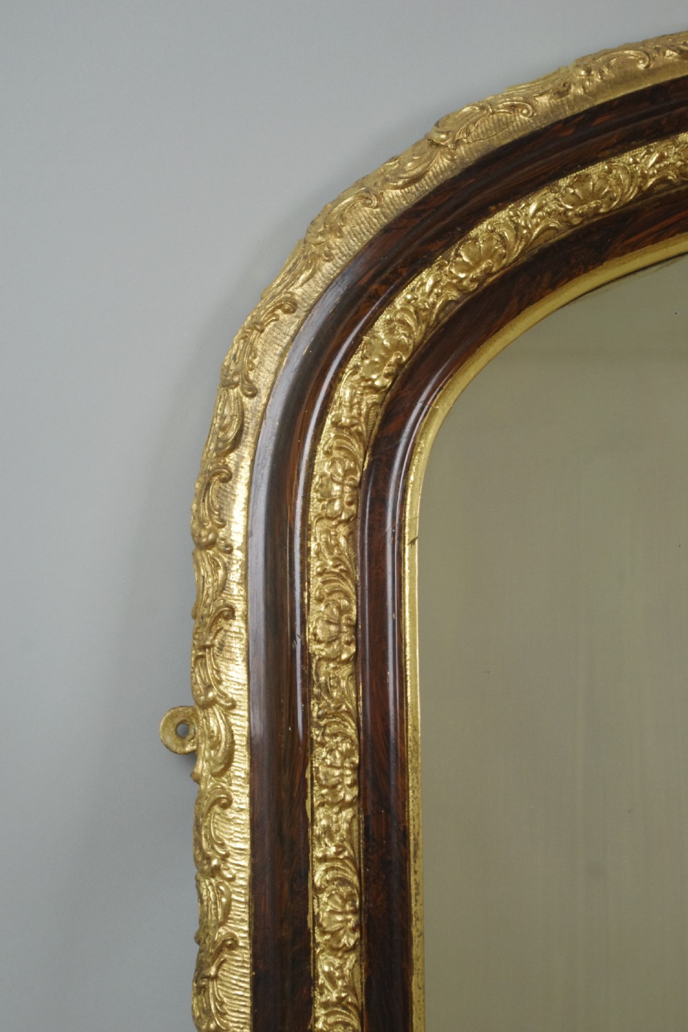 A large Victorian arched overmantel mirror featuring a simulated dark wood frame with detailed parcel-gilt foliage moulding along the inner and outer borders. View III
