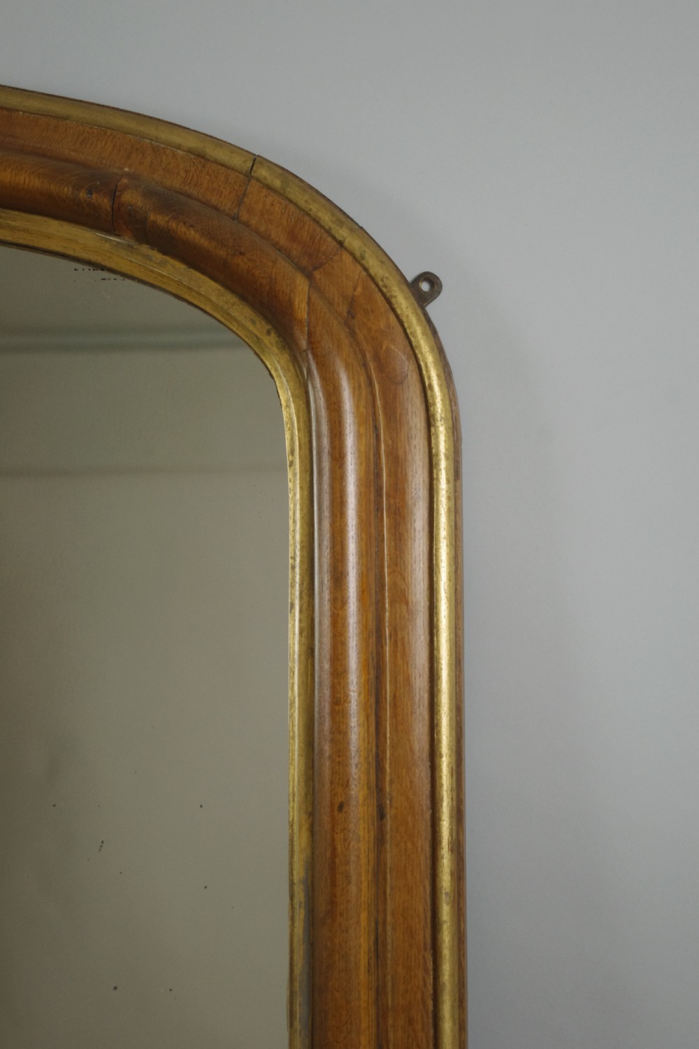 A large Victorian arch-top overmantel mirror with a moulded oak frame, parcel-gilt inner rim, and carved scroll bases. View IV