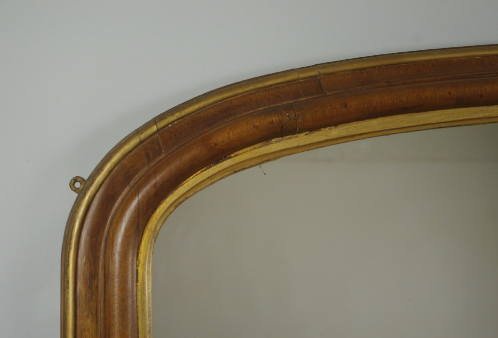 A large Victorian arch-top overmantel mirror with a moulded oak frame, parcel-gilt inner rim, and carved scroll bases. View V