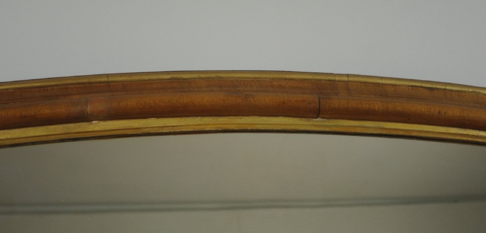 A large Victorian arch-top overmantel mirror with a moulded oak frame, parcel-gilt inner rim, and carved scroll bases. View VII