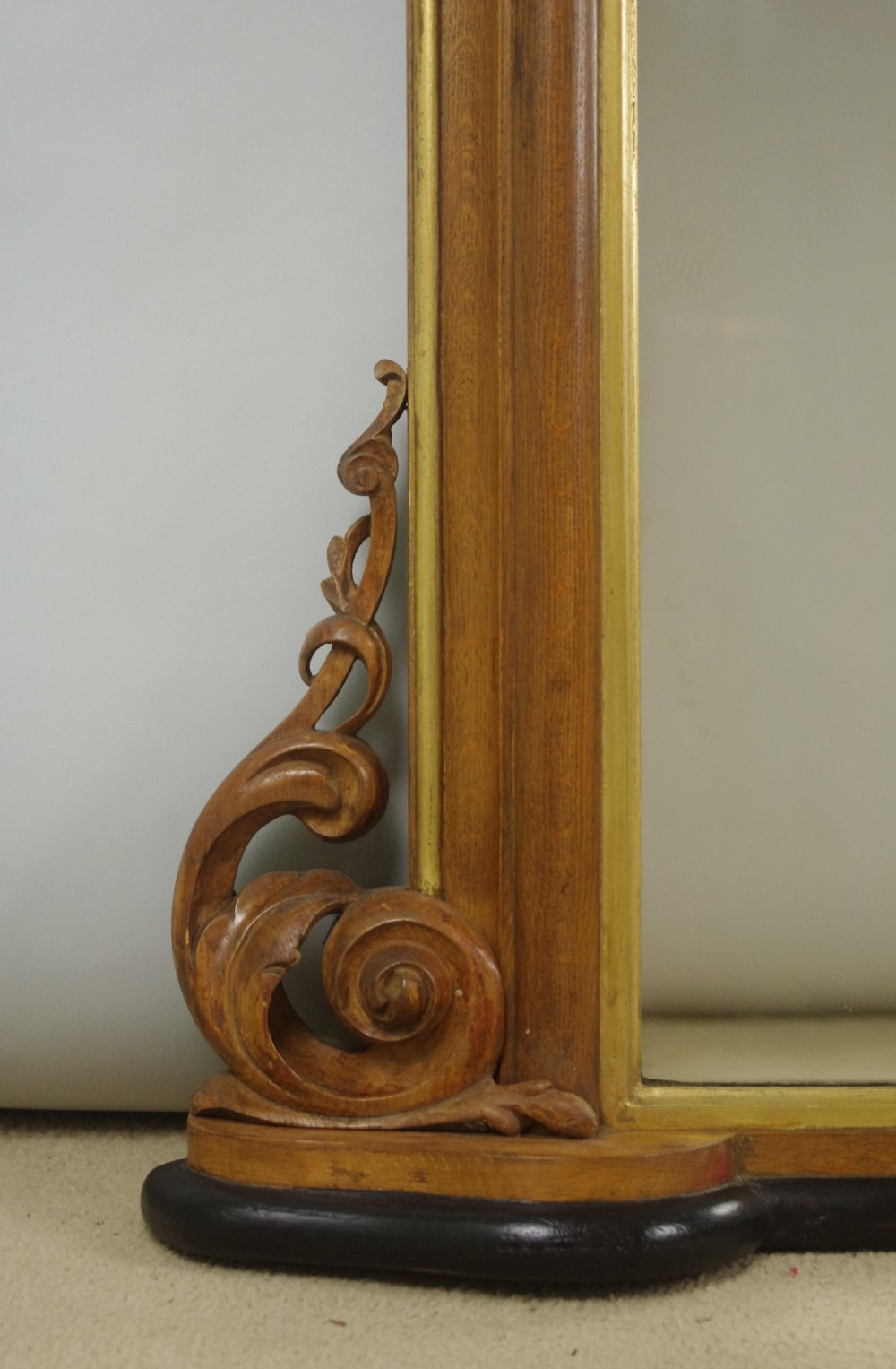 A large Victorian arch-top overmantel mirror with a moulded oak frame, parcel-gilt inner rim, and carved scroll bases. View VIII