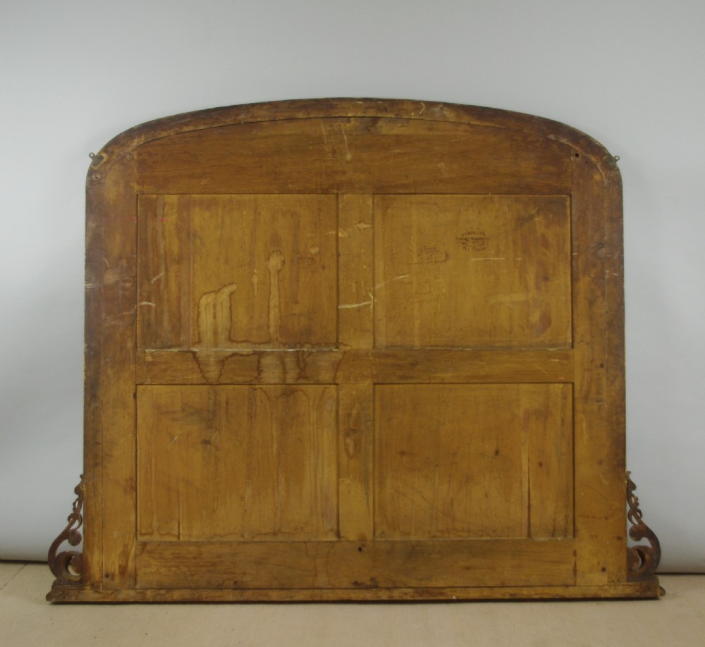 A large Victorian arch-top overmantel mirror with a moulded oak frame, parcel-gilt inner rim, and carved scroll bases. View XI