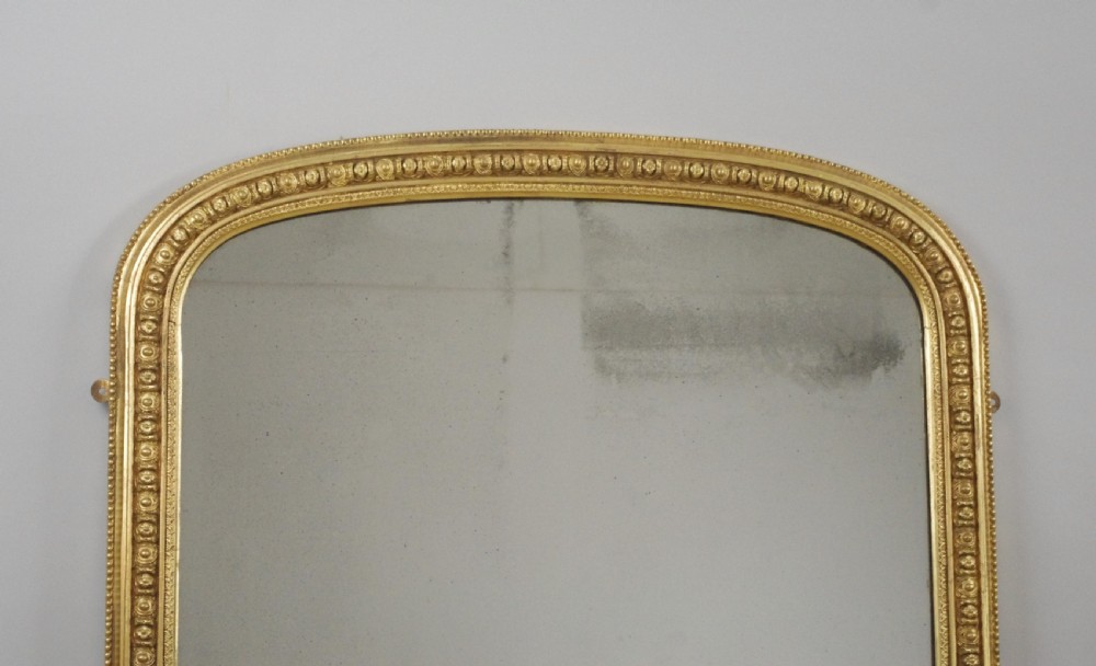 A Victorian giltwood overmantel mirror featuring an arched top frame, beaded relief moulding, and decorative scrollwork supports at the base. View II