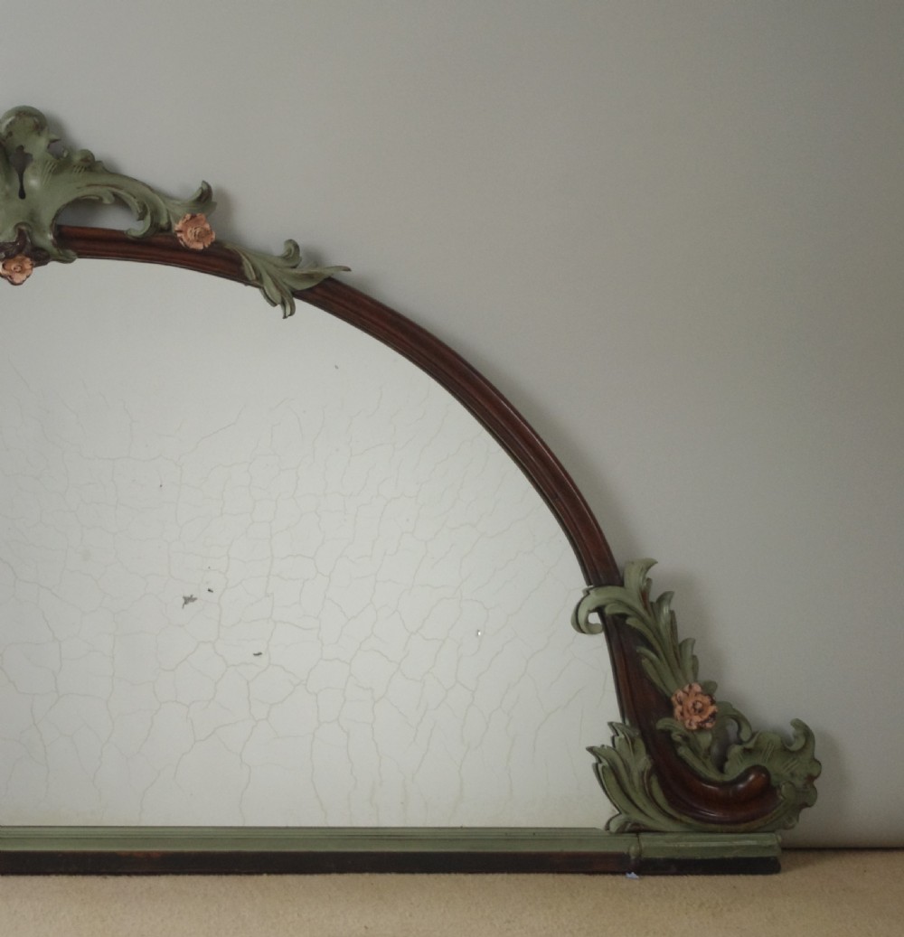 A Victorian arch-top mahogany overmantel mirror with carved sage green scrolling foliage and pale pink painted flowers around the frame. View VI