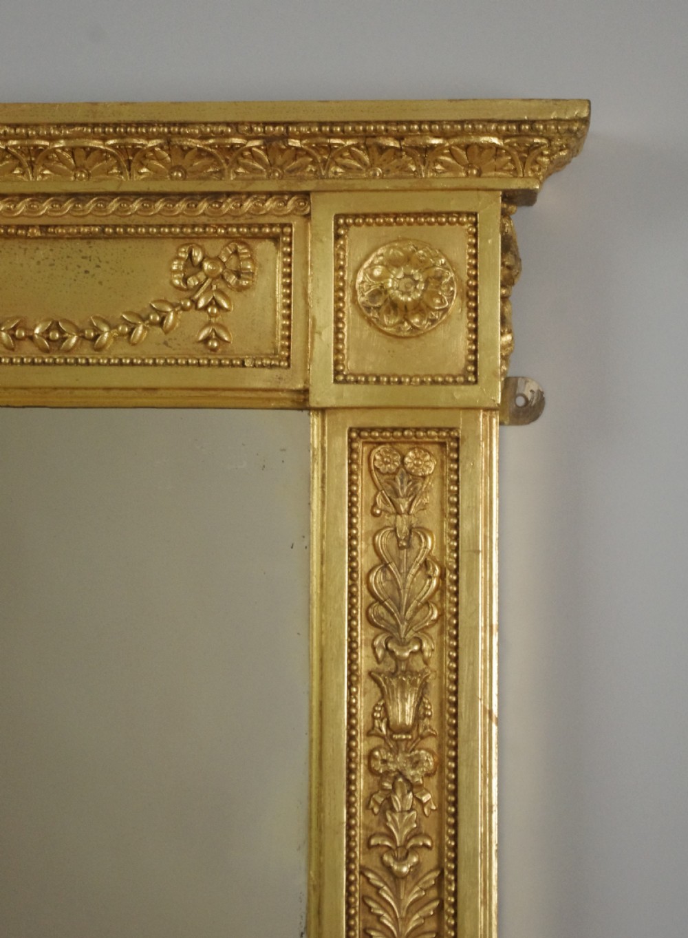 A large rectangular Victorian gilt overmantel mirror featuring Neoclassical swags, rosettes, and beaded moulding along the frame. View VI