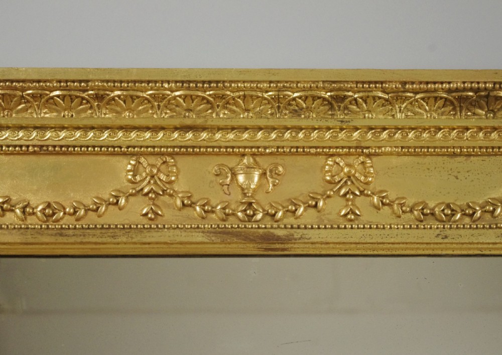A large rectangular Victorian gilt overmantel mirror featuring Neoclassical swags, rosettes, and beaded moulding along the frame. View VII