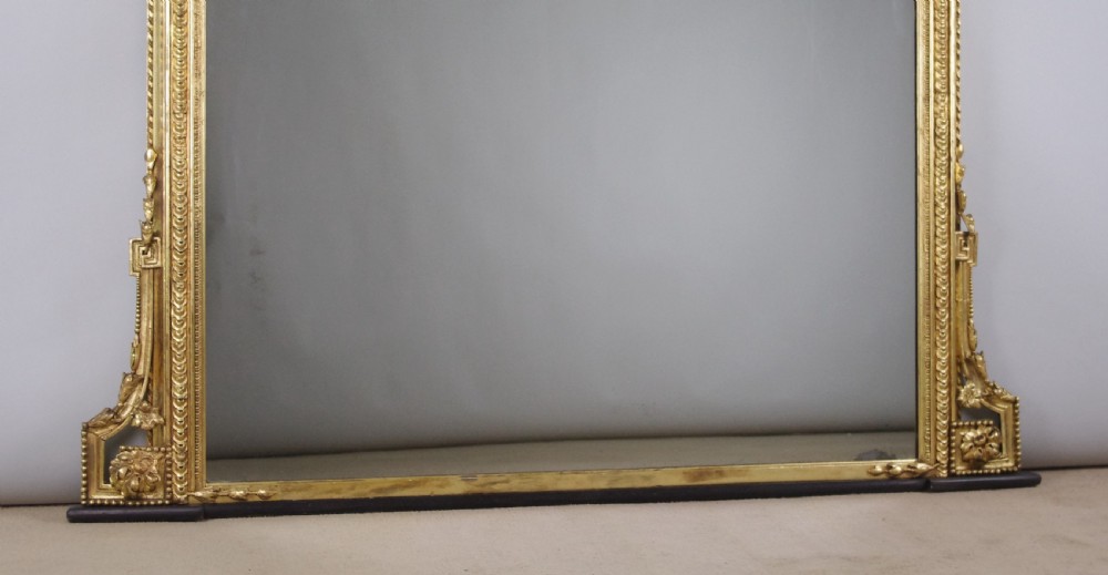 A large Victorian giltwood overmantel mirror featuring an arched top frame topped with an elaborate carved shell cresting. View IX