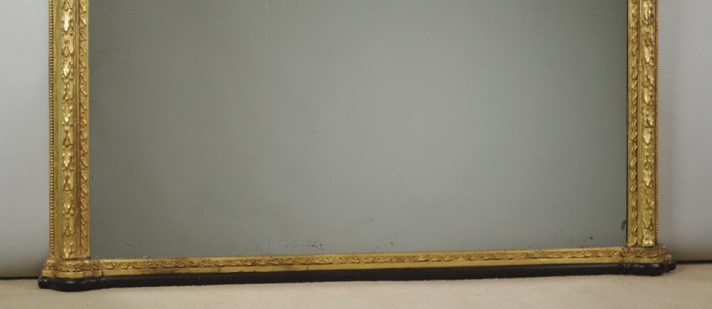 A large Victorian arched overmantel mirror featuring a gold giltwood frame with leaf moulding and a flat base. View VII