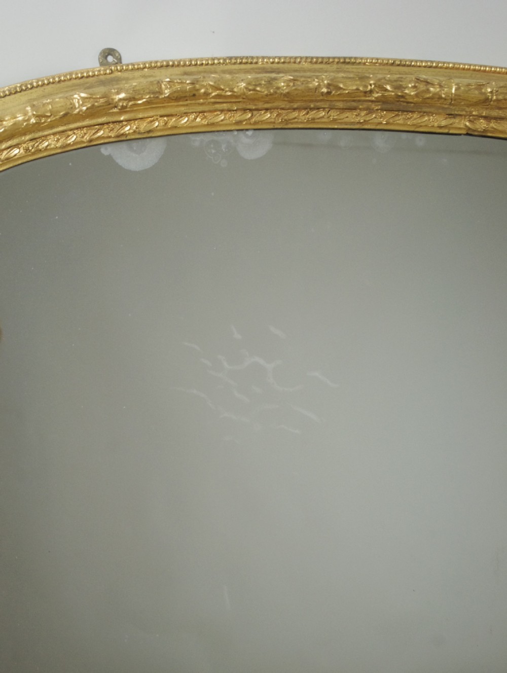 A large Victorian arched overmantel mirror featuring a gold giltwood frame with leaf moulding and a flat base. View VIII