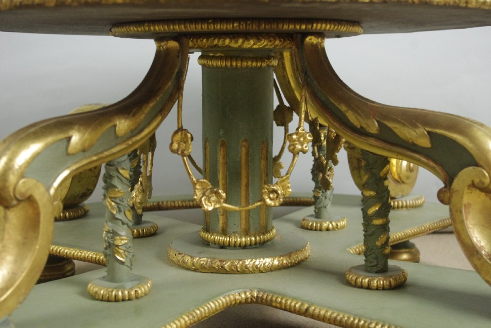 A low circular French Neoclassical style centre table featuring a dark green marble top and a sage green painted base with carved parcel-gilt scroll supports. View IX