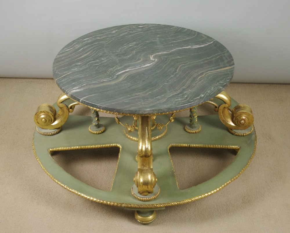A low circular French Neoclassical style centre table featuring a dark green marble top and a sage green painted base with carved parcel-gilt scroll supports. View X