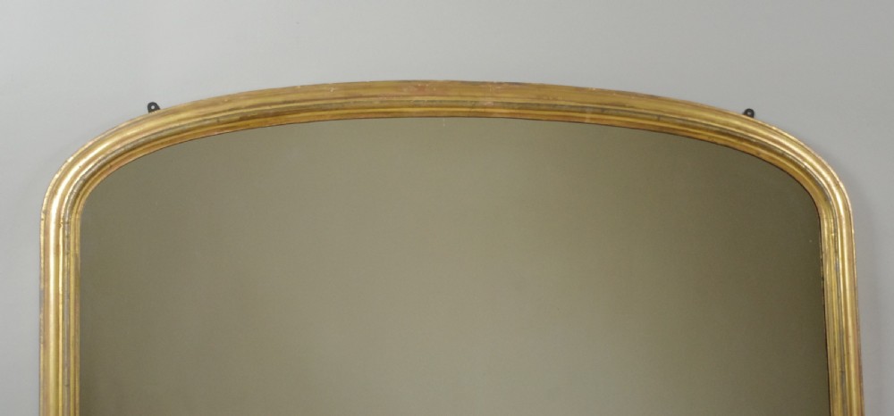 A large Victorian arched overmantel mirror featuring a gilded wood frame with decorative scroll side corbels. View III