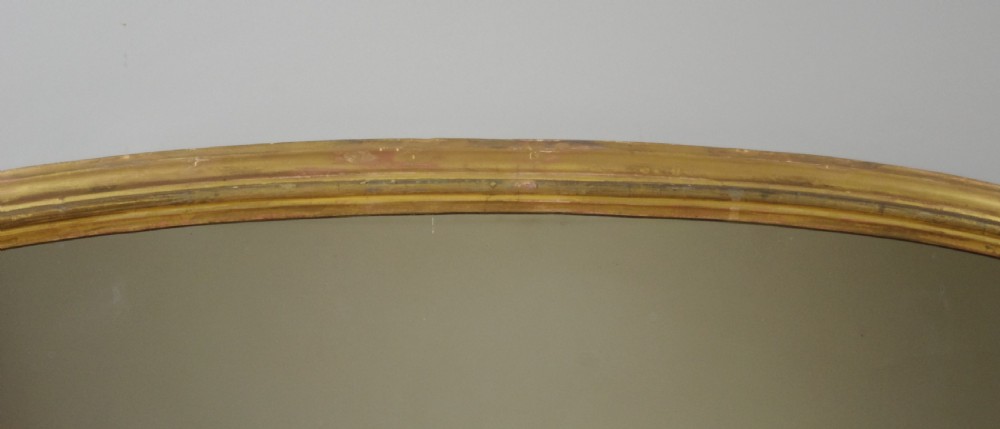 A large Victorian arched overmantel mirror featuring a gilded wood frame with decorative scroll side corbels. View VII