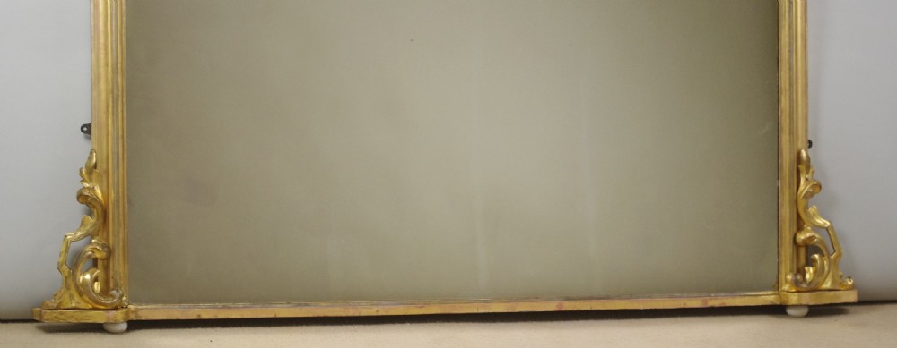 A large Victorian arched overmantel mirror featuring a gilded wood frame with decorative scroll side corbels. View X