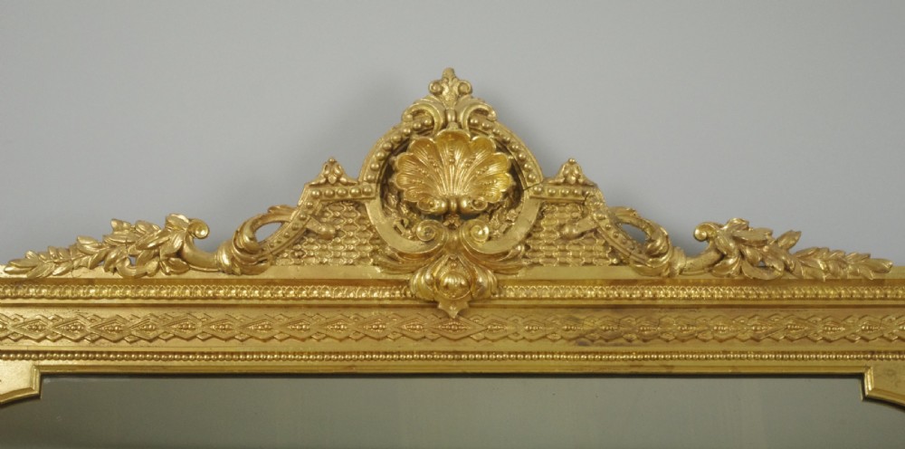 A large Victorian gold gilded overmantel mirror featuring an ornate shell crest pediment and slender side columns. View III
