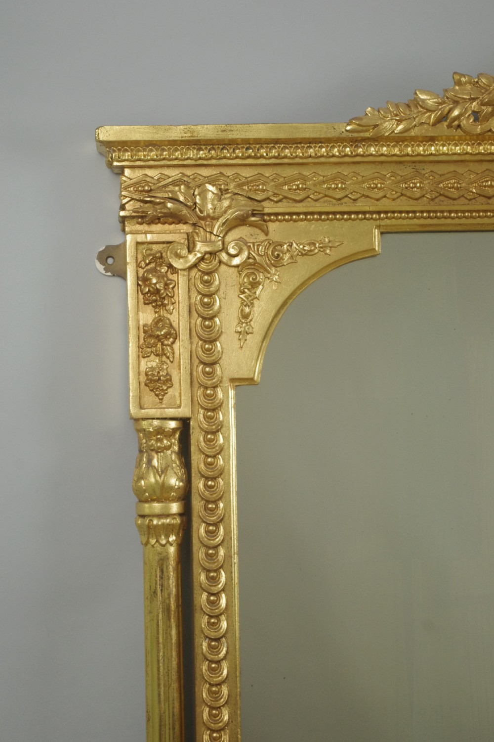 A large Victorian gold gilded overmantel mirror featuring an ornate shell crest pediment and slender side columns. View V