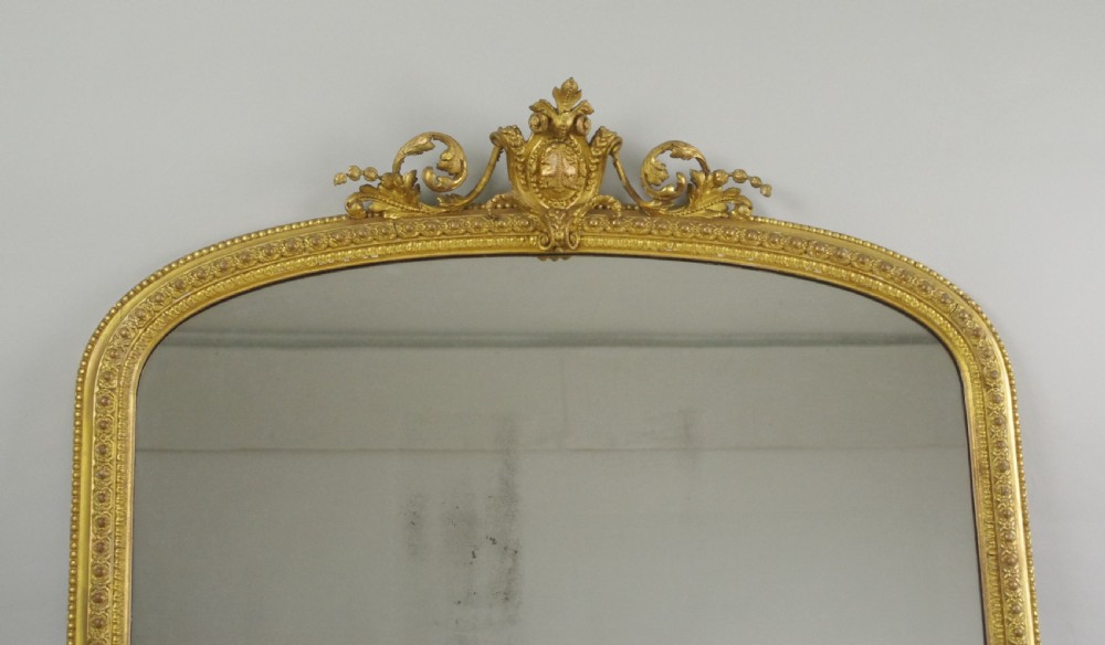 A large Victorian overmantel mirror featuring an arched gold leaf frame with cresting and beaded details. View II