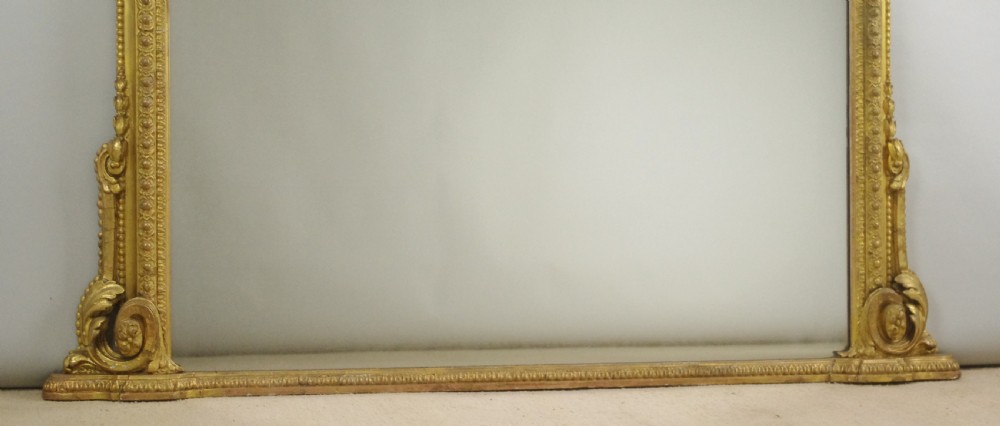 A large Victorian overmantel mirror featuring an arched gold leaf frame with cresting and beaded details. View IX