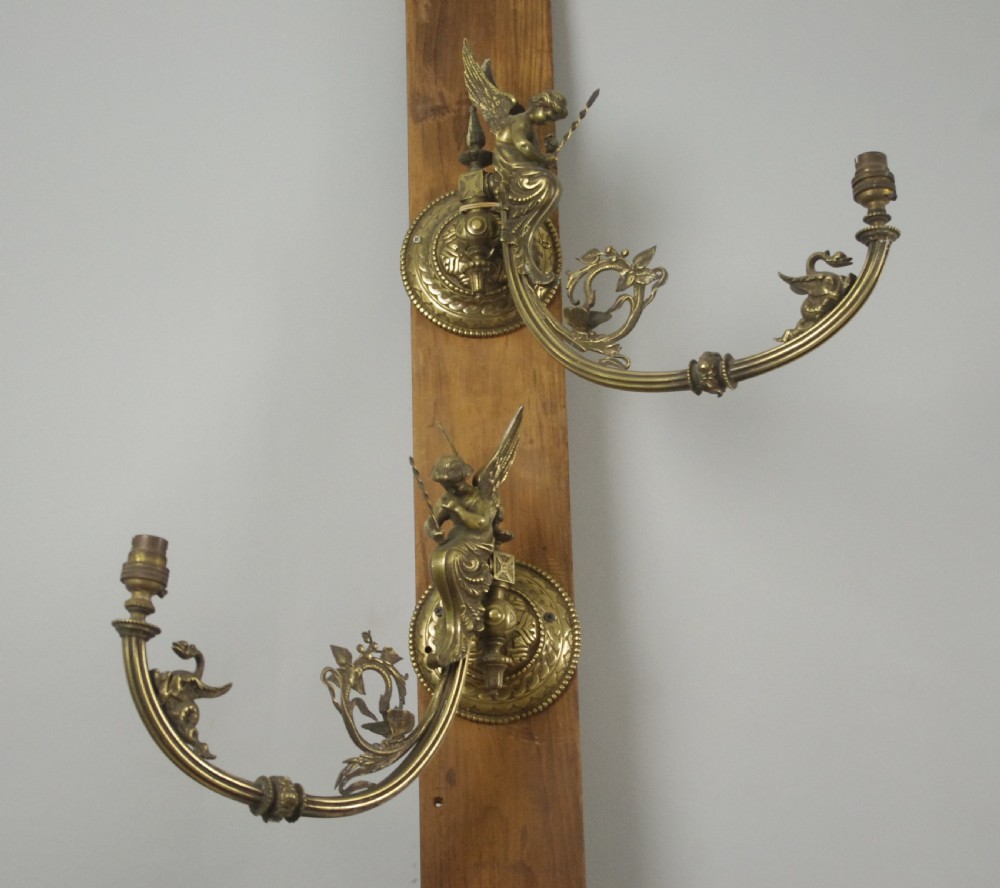 A pair of cast brass Victorian wall sconces featuring sculpted cherubs, mythological creature accents, and ornamental scroll arms. View II