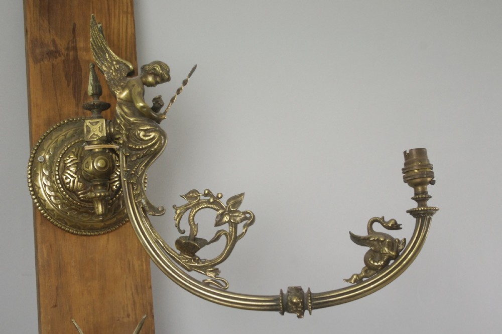 A pair of cast brass Victorian wall sconces featuring sculpted cherubs, mythological creature accents, and ornamental scroll arms. View IV