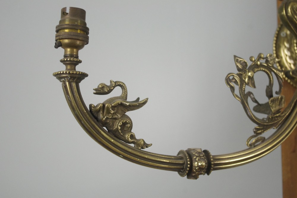 A pair of cast brass Victorian wall sconces featuring sculpted cherubs, mythological creature accents, and ornamental scroll arms. View X