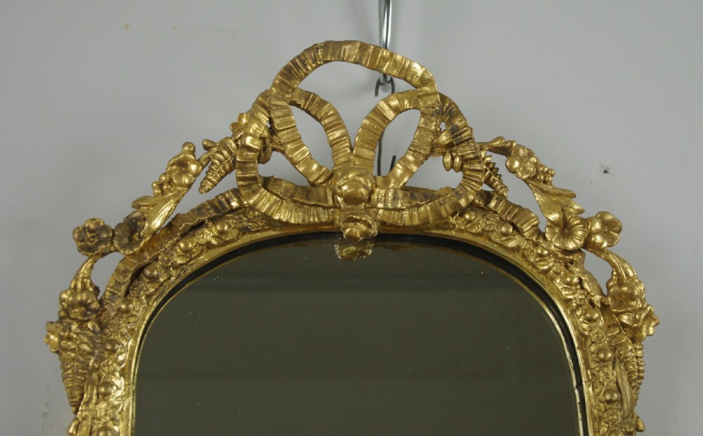 A matching pair of Victorian giltwood wall shelves featuring mirrored backs, ornate bow cresting, and open tiers for displaying small objects. View VII