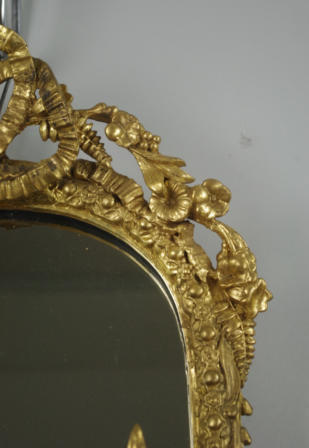 A matching pair of Victorian giltwood wall shelves featuring mirrored backs, ornate bow cresting, and open tiers for displaying small objects. View X