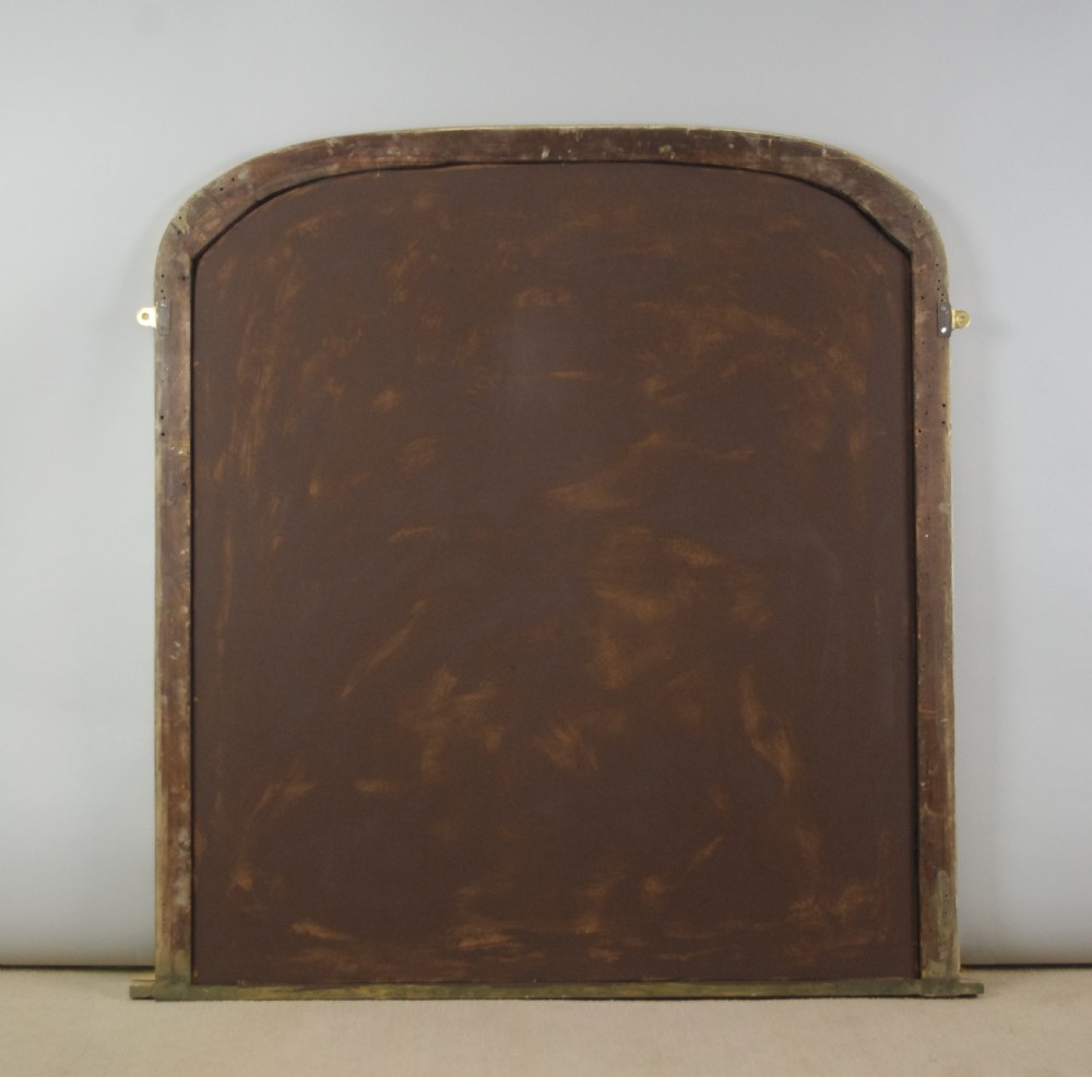 A large Victorian giltwood overmantel mirror with a curved arched top and moulded frame. View IX