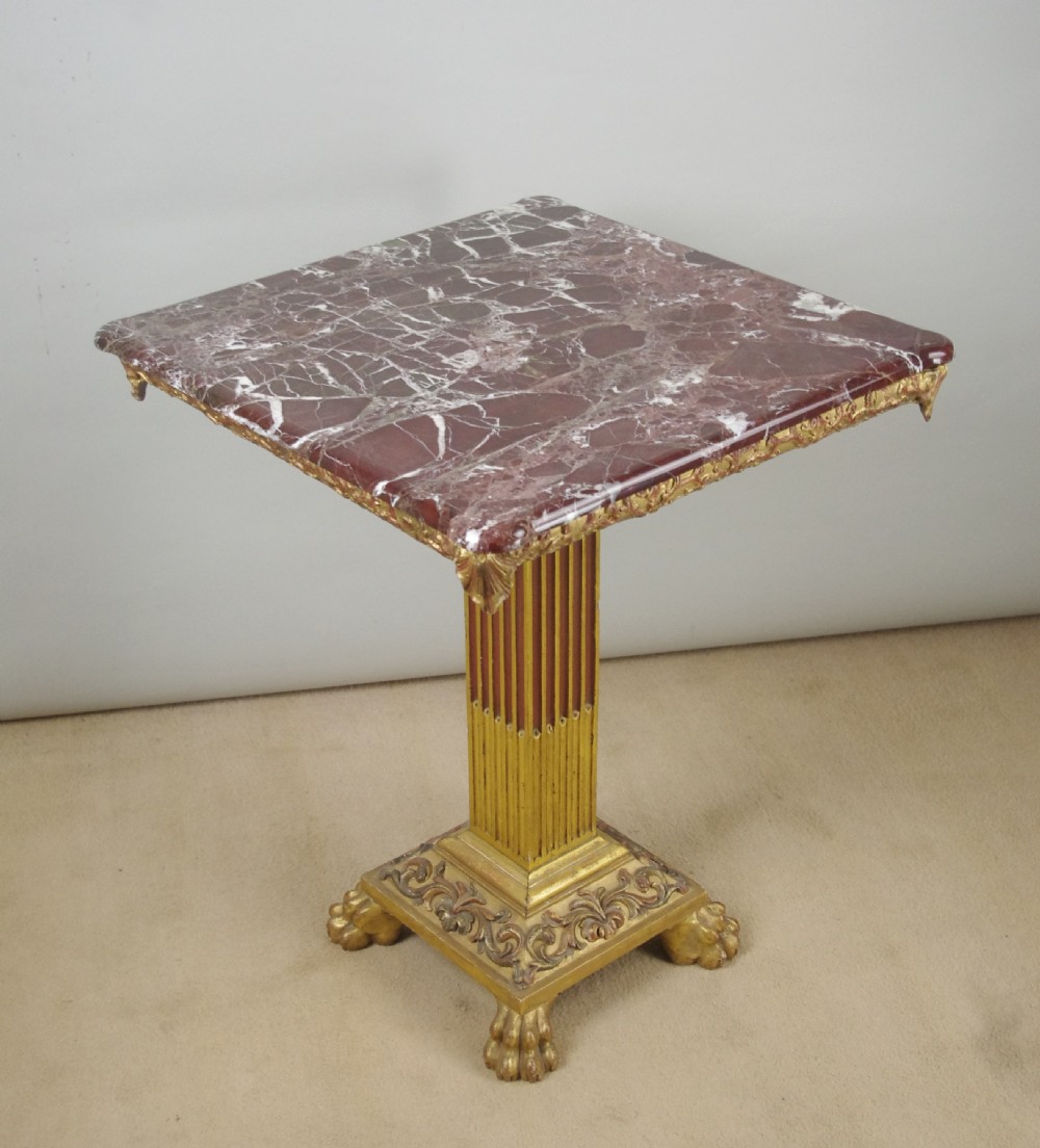 A square Victorian occasional table featuring a red veined marble top resting on a giltwood fluted pedestal with lion paw feet. View II
