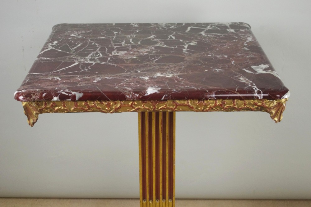 A square Victorian occasional table featuring a red veined marble top resting on a giltwood fluted pedestal with lion paw feet. View V