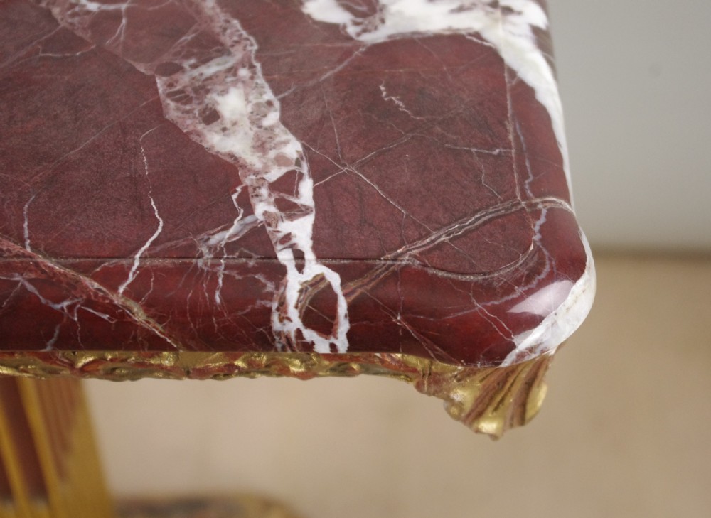 A square Victorian occasional table featuring a red veined marble top resting on a giltwood fluted pedestal with lion paw feet. View X