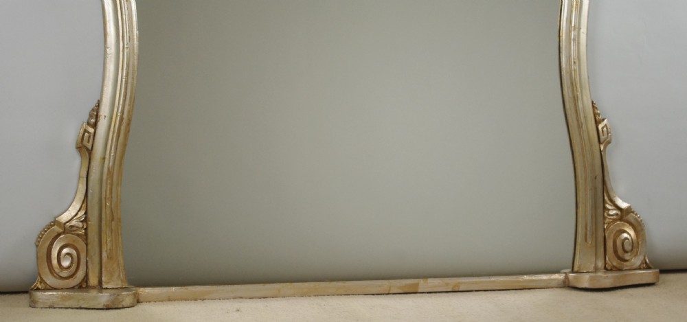 A Victorian silvered overmantel mirror featuring an arched upper frame, molded detailing, and decorative scroll motifs at the base. View VIII