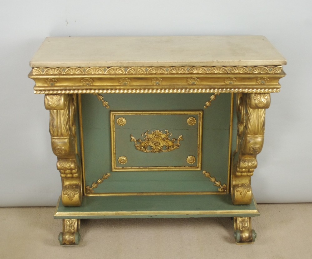 A 19th-century French console table with a cream marble top, green painted base, gilding, and large scroll legs. View V
