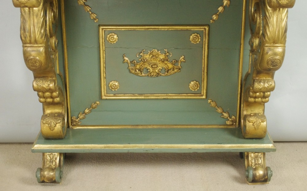 A 19th-century French console table with a cream marble top, green painted base, gilding, and large scroll legs. View VII