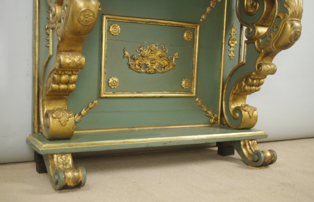 A 19th-century French console table with a cream marble top, green painted base, gilding, and large scroll legs. View IX