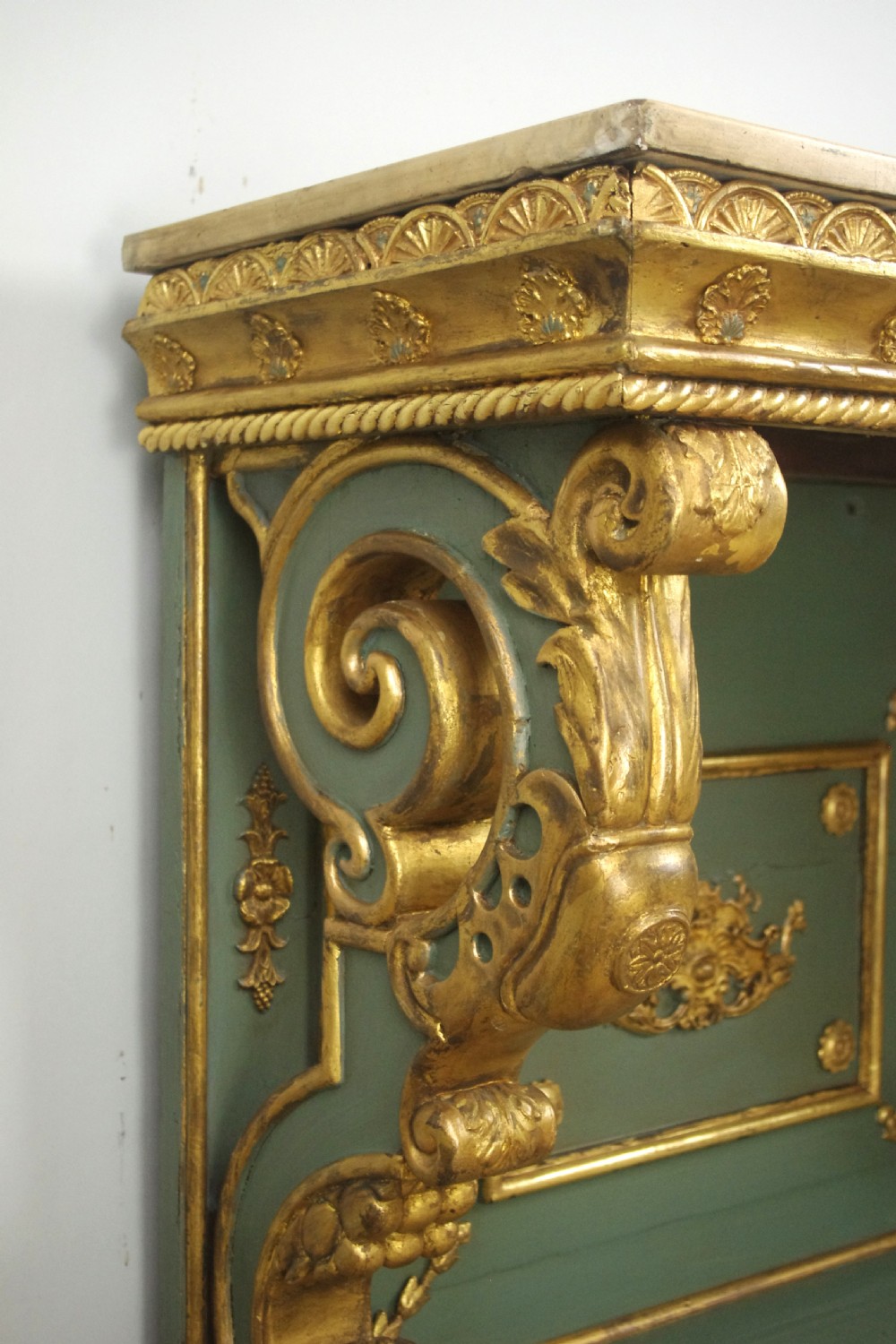 A 19th-century French console table with a cream marble top, green painted base, gilding, and large scroll legs. View X