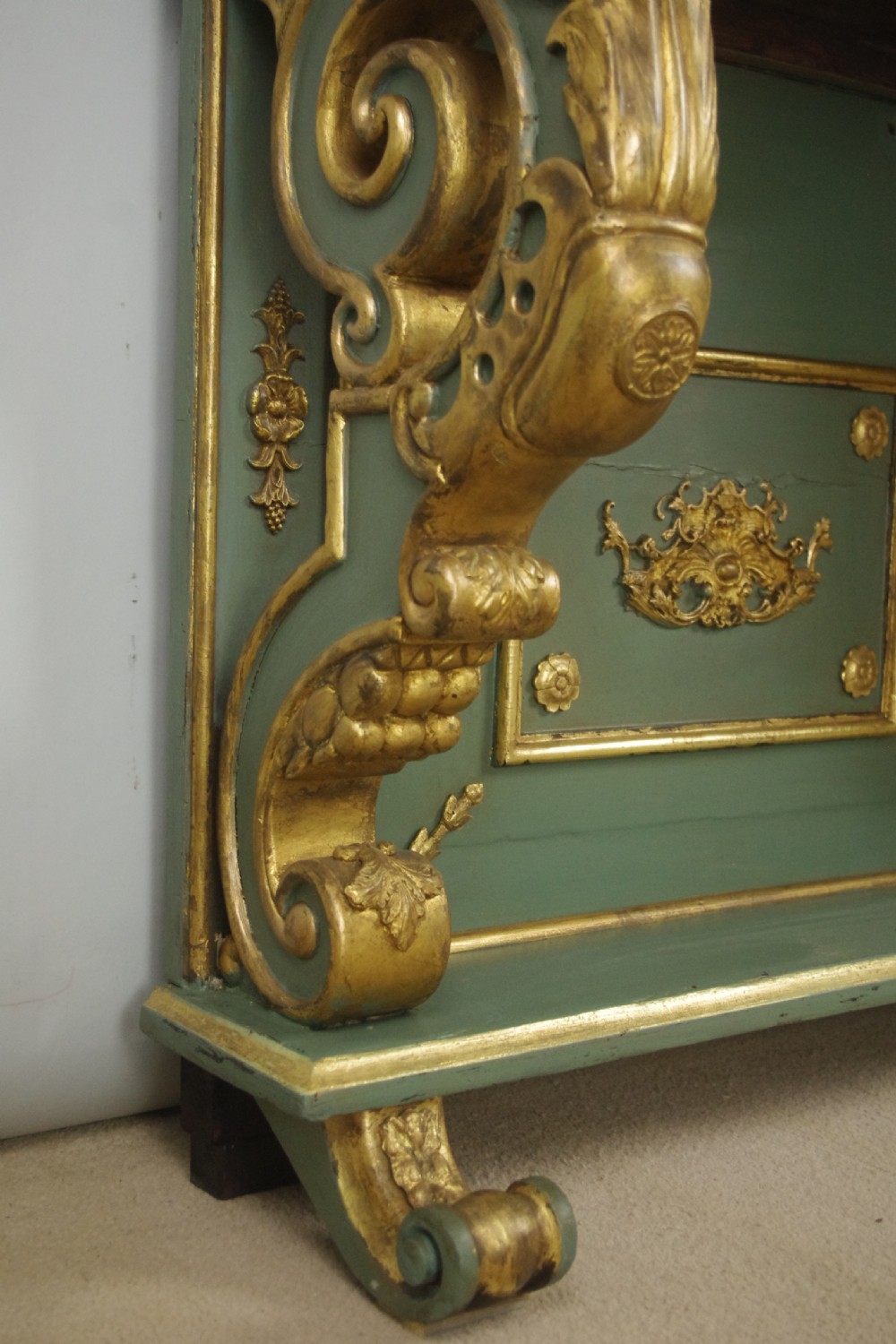 A 19th-century French console table with a cream marble top, green painted base, gilding, and large scroll legs. View XI