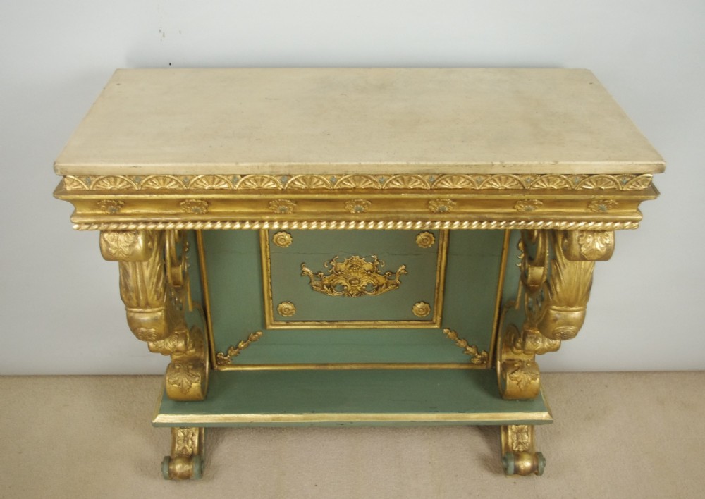 A 19th-century French console table with a cream marble top, green painted base, gilding, and large scroll legs. View XVII