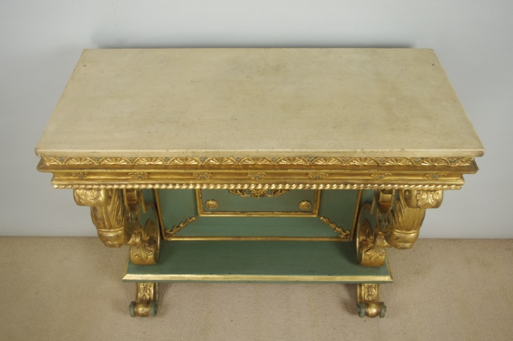 A 19th-century French console table with a cream marble top, green painted base, gilding, and large scroll legs. View XVIII