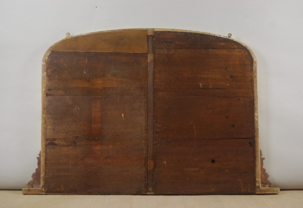 A large Victorian arched overmantel mirror featuring a gilded frame with carved scroll moulding details at the bottom corners. View VIII