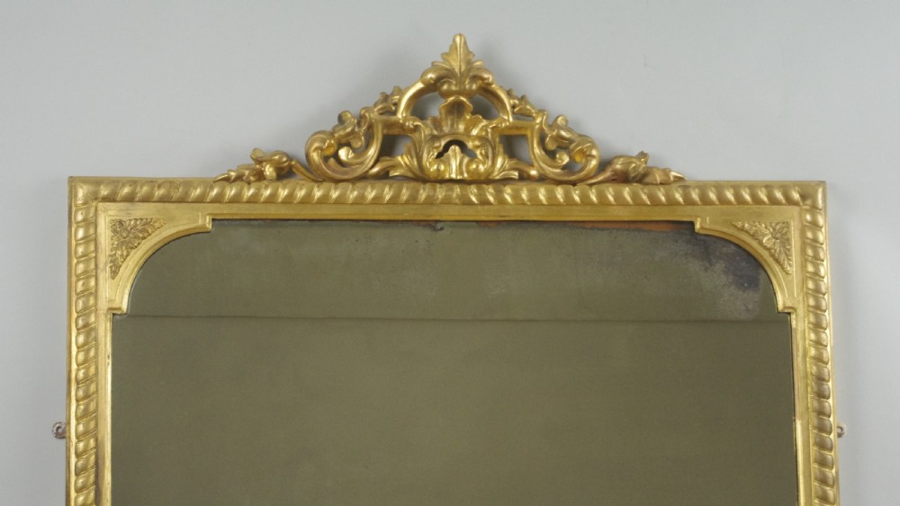 A large Victorian giltwood overmantel mirror featuring rope-twist moulding, a carved top cresting, and scroll corner feet. View II