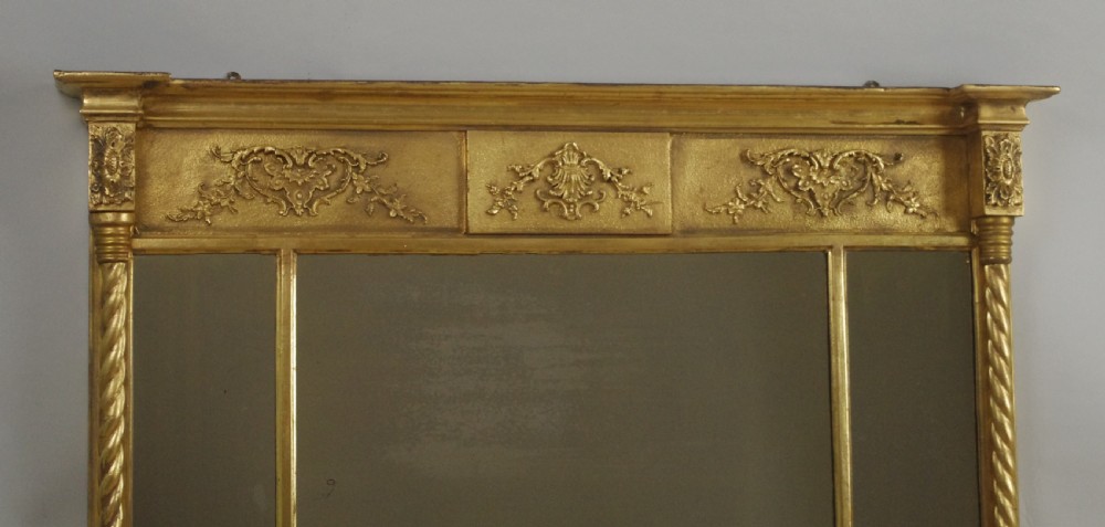 A horizontal Victorian giltwood overmantel mirror with three mirror glass panels, decorative floral relief friezes, and rope-twist side columns. View IV