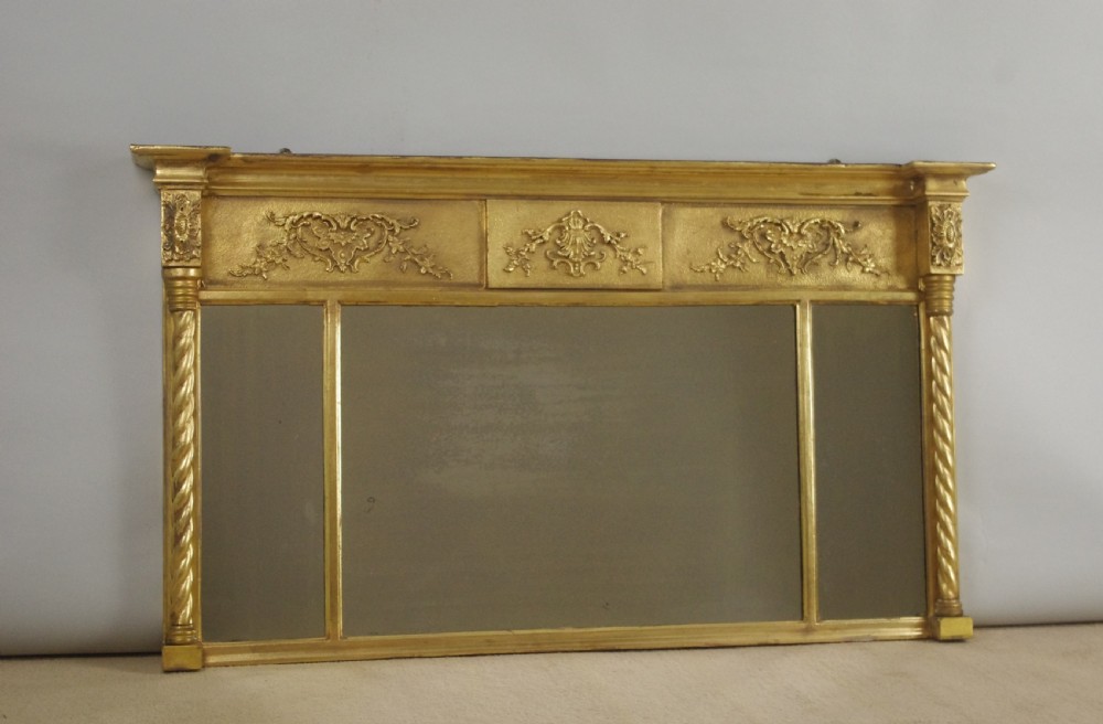 A horizontal Victorian giltwood overmantel mirror with three mirror glass panels, decorative floral relief friezes, and rope-twist side columns. View IX