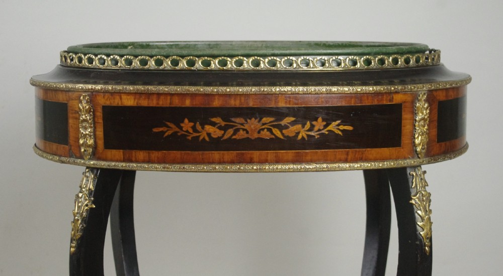 A 19th-century French oval ebonised jardiniere table featuring floral marquetry frieze, gilt-bronze mounts, cabriole legs, and a green metal liner with a pierced brass gallery. View IV