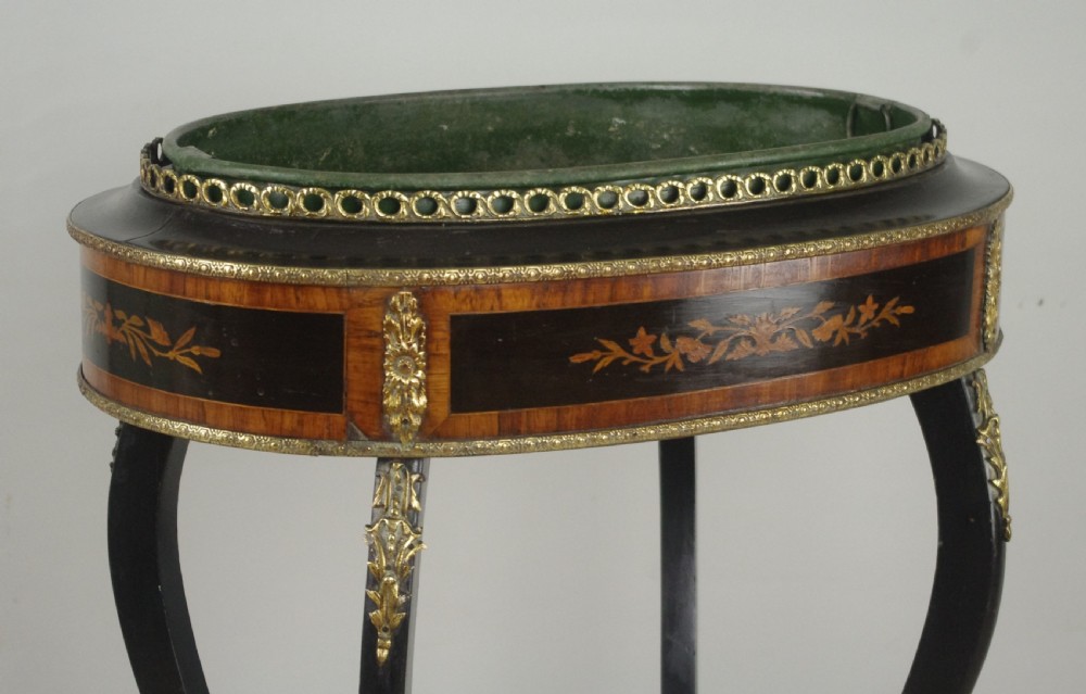 A 19th-century French oval ebonised jardiniere table featuring floral marquetry frieze, gilt-bronze mounts, cabriole legs, and a green metal liner with a pierced brass gallery. View V