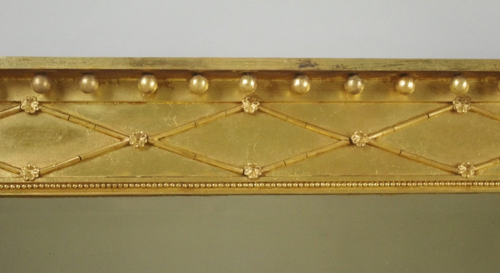 A wide rectangular Victorian giltwood overmantel mirror featuring three mirror plates, fluted side columns, and an ornamental frieze with diamond motifs. View VI